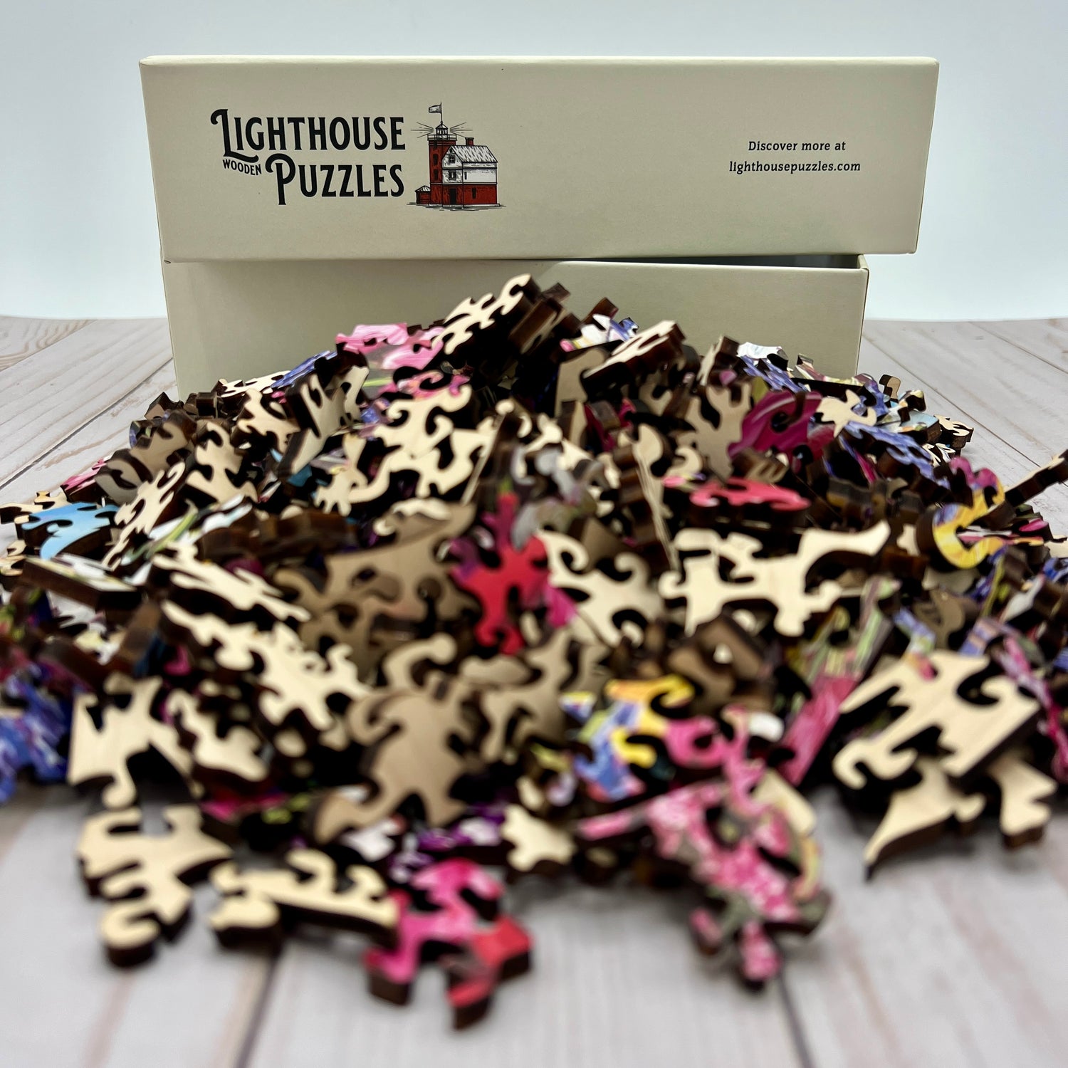 A pile of wooden jigsaw pieces placed in front of an empty box.