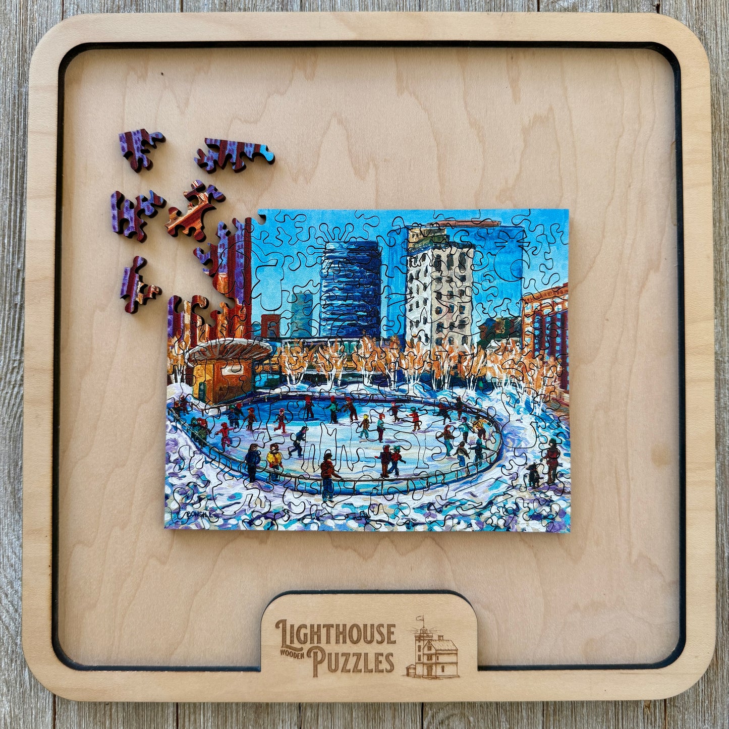 Downtown Ice Skating winter scene puzzle in a wooden tray with loose pieces ready for assembly.